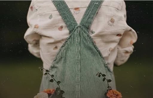 Criança de jardineira segurando flores